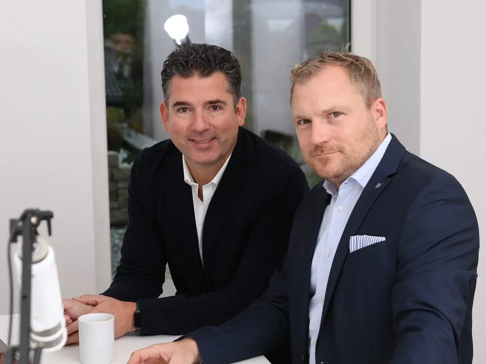 Thomas und Florian Stahl sitzen nebeneinander am Tisch, vorne ein Mikrofon